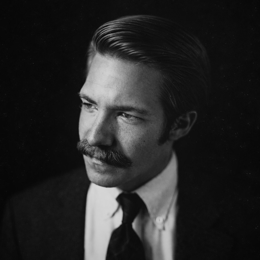 Black-and-white portrait photograph of Dan Meyer, in profile, wearing a dark suit and tie